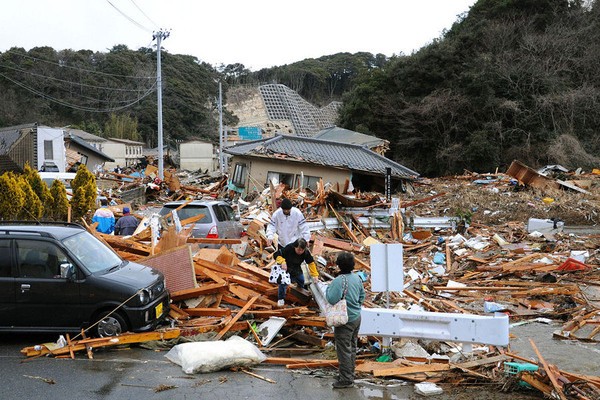 日本福岛县磐城市,人们走在地震后的房屋废墟上